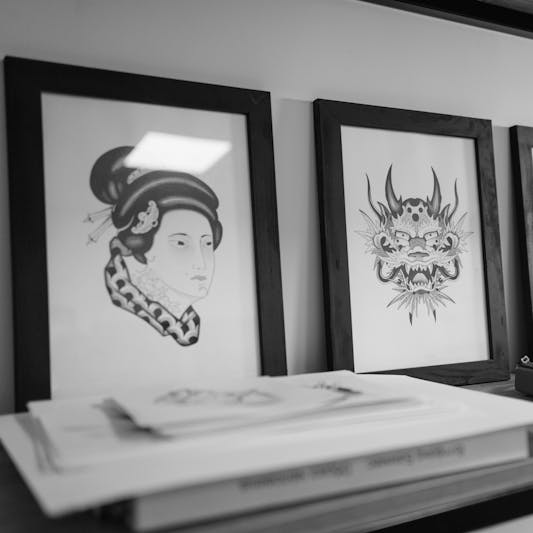 Monochrome art prints and compact synthesizer placed on a sleek shelf in an indoor setting.
